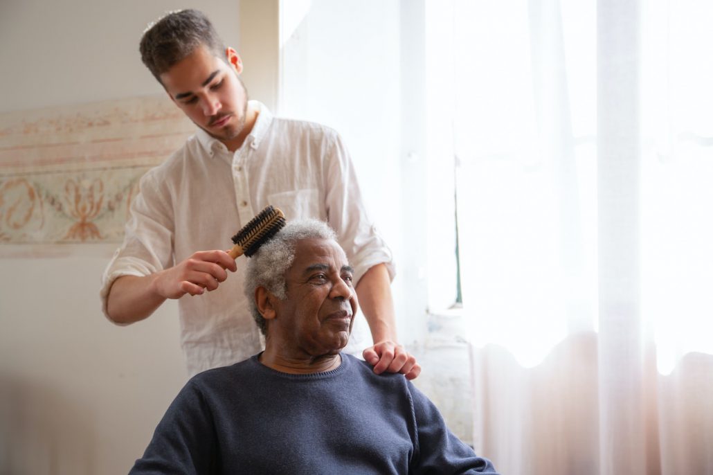 senior home care, man helping older man brush his hair